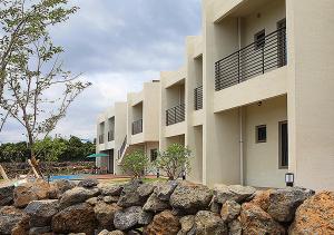 a building with a stone fence in front of it at Comma&Spa Resort in Seogwipo