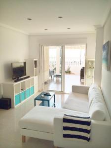 un soggiorno con divano bianco e TV di Beach Front Ground Floor Flat Playa San Juan a El Campello