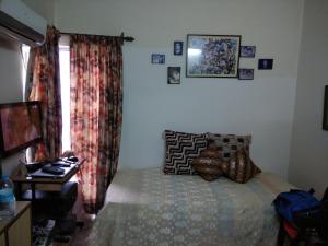 1 dormitorio con 1 cama, TV y ventana en Joy's Nest, en Calcuta