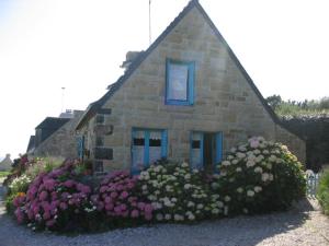 una pequeña casa de piedra con flores delante en lemoign-locations, en Crozon