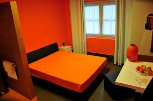 Habitación pequeña con cama naranja y mesa. en Ai Lecci in Centro en Sarteano