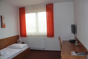una camera da letto con un letto, una finestra e una scrivania di Hotel Olympionik a Mělník