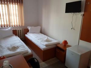 ファガラシュにあるPiete Targuri Si Oboareのベッド2台とテレビが備わる小さな客室です。