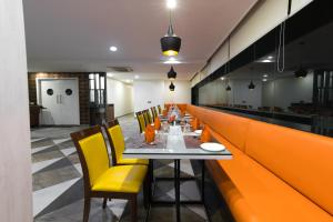 a long dining room with a long table and yellow chairs at Kyriad Hotel Gulbarga by OTHPL in Gulbarga