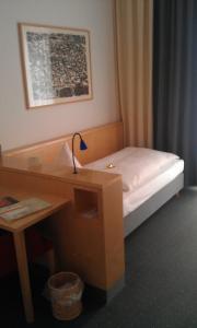 a small bedroom with a desk and a bed at Hôtel Galerie in Greifswald