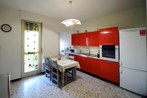 ベーネ・ヴァジエンナにあるBene Vagienna Holiday Houseのキッチン(赤いキャビネット、テーブル、冷蔵庫付)