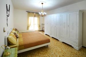 een slaapkamer met een bed met witte kasten en een kroonluchter bij Bene Vagienna Holiday House in Bene Vagienna