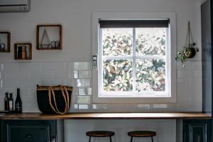 a kitchen counter with two stools and a window at Northfield Boutique Apartments in Woodend