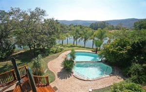 een zwembad naast een rivier met bomen bij Kruger Park Lodge 401 in Hazyview
