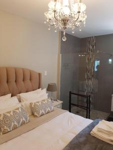 a bedroom with a large bed with a chandelier at Emmaus-On-Sea in Yzerfontein