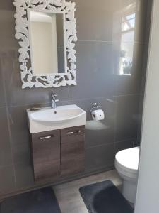 a bathroom with a sink and a mirror and a toilet at Emmaus-On-Sea in Yzerfontein