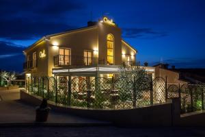 une maison avec une clôture devant elle la nuit dans l'établissement Holiday home ''Oasi'', à Pula