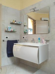 W łazience znajduje się biała umywalka i lustro. w obiekcie Appartamento corso Garibaldi w mieście Porto Cesareo