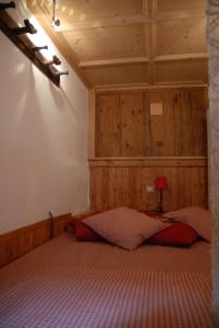 a bedroom with a bed with a wooden wall at Casetta Villa in Villa di Chiavenna