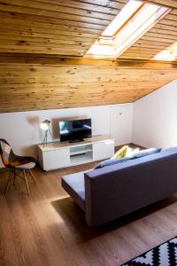 リスボンにあるOur Friends Apartmentのソファとテレビ付きのベッドルーム1室、木製の天井が備わります。