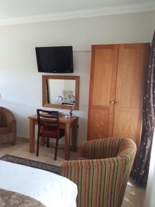 una habitación con un escritorio, una silla y un espejo en Hoyohoyo Chartwell Lodge, en Johannesburgo
