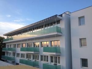 una vista esterna di un edificio bianco con balconi verdi di Hotel Aurum Family "A" a Hajdúszoboszló