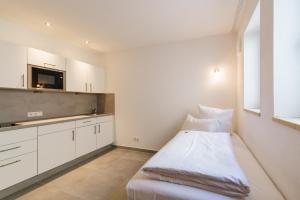 a white room with a bed and a kitchen at DuDa Boarding Apartments in Langenbruck