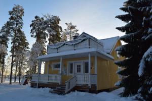 una casa amarilla con nieve en el techo en Laiskan Kartano en Härmä