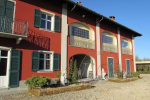 a red house with green shutters on it at B&B Cascina Rossa in Asti