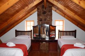 a attic room with two beds and a stone wall at Critchley Hackle - Managers Cottage in Dullstroom