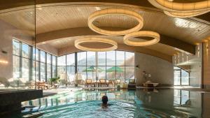 a person swimming in a pool in a building at Bergland Design- und Wellnesshotel in Sölden