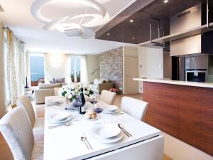 una cucina e un soggiorno con tavolo e sedie bianchi di State of the art home suite with 180° panoramic lake view, pool, sauna & jacuzzi a Como