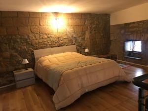 a bedroom with a bed and a stone wall at Palazzo Urbani in Orvieto