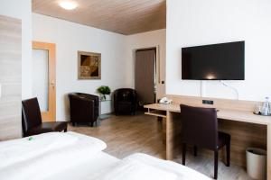a room with a desk with chairs and a flat screen tv at Hotel Palko in Dingolfing