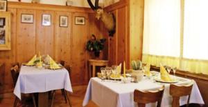 een eetkamer met twee tafels met witte tafelkleden bij Gasthaus Alte Post in Zillis