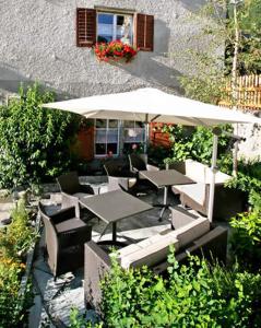 a patio with tables and chairs and an umbrella at Gasthaus Alte Post in Zillis