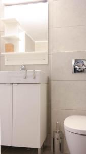 La salle de bains blanche est pourvue d'un lavabo et de toilettes. dans l'établissement Modern Downtown Flat near the Acropolis by UPSTREET, à Athènes