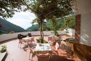 patio ze stołami, krzesłami i drzewem w obiekcie B&B Bouganville w mieście Tramonti