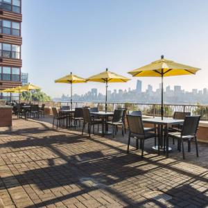 una fila de mesas y sillas con sombrillas amarillas en Global Luxury Suites at Hoboken Waterfront, en Hoboken
