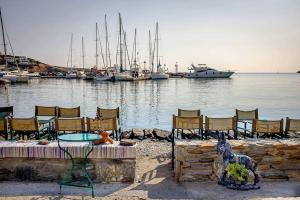 a woman sitting on a table next to a marina at Loutra House Kythnos in Loutra