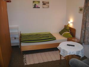 a small bedroom with a bed and a table at Pension Reindlhöh in Lohberg