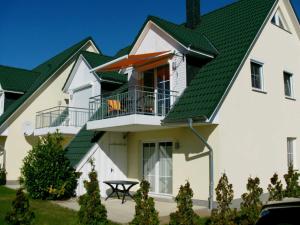 une grande maison blanche avec un toit vert dans l'établissement Fewo Dat Ole_ZECH, à Karlshagen