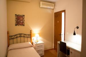 - une chambre avec un lit et un bureau avec une lampe dans l'établissement Pensión y apartamentos El Taxi, à Casabermeja