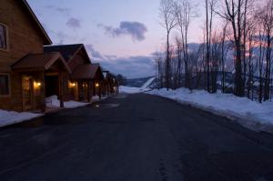 an empty road in the snow next to a building at The Lodges at Sunset Village in McHenry