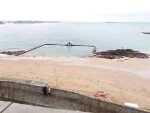 a man standing on a beach next to a swimming pool at Le Chateaubriand by Cocoonr in Saint Malo
