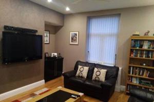 a living room with a leather couch and a flat screen tv at Bonny Colne On The Hill in Colne