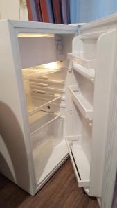 an empty refrigerator with its door open in a kitchen at Hotel Feria (FR) in Clichy