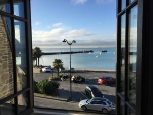 ein Fenster mit Blick auf einen Parkplatz und einen Hafen in der Unterkunft Bel appartement vue sur mer in Cancale