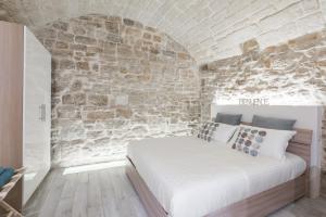 sypialnia z łóżkiem w kamiennej ścianie w obiekcie San Nicola Old Town Apartment Casatuabari w mieście Bari