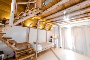 a loft bed in a room with wooden ceilings at Baladin Zanzibar Beach Hotel in Michamvi