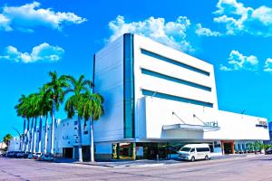 biały budynek z palmami przed nim w obiekcie Hotel Plaza Inn w mieście Los Mochis