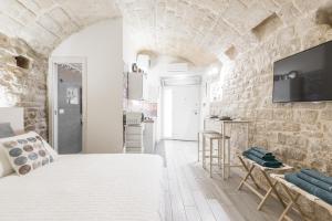 sypialnia z białym łóżkiem i kamienną ścianą w obiekcie San Nicola Old Town Apartment Casatuabari w mieście Bari