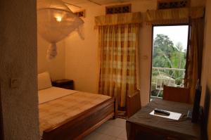 a bedroom with a bed and a window and a table at Ubumwe Hotel in Gisenyi