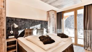 
a bedroom with a large bed and a large window at Mountain Spa Residences in Sankt Anton am Arlberg
