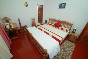 1 dormitorio con 1 cama grande con sábanas rojas y blancas en Mulberry Homestay, en Thekkady
